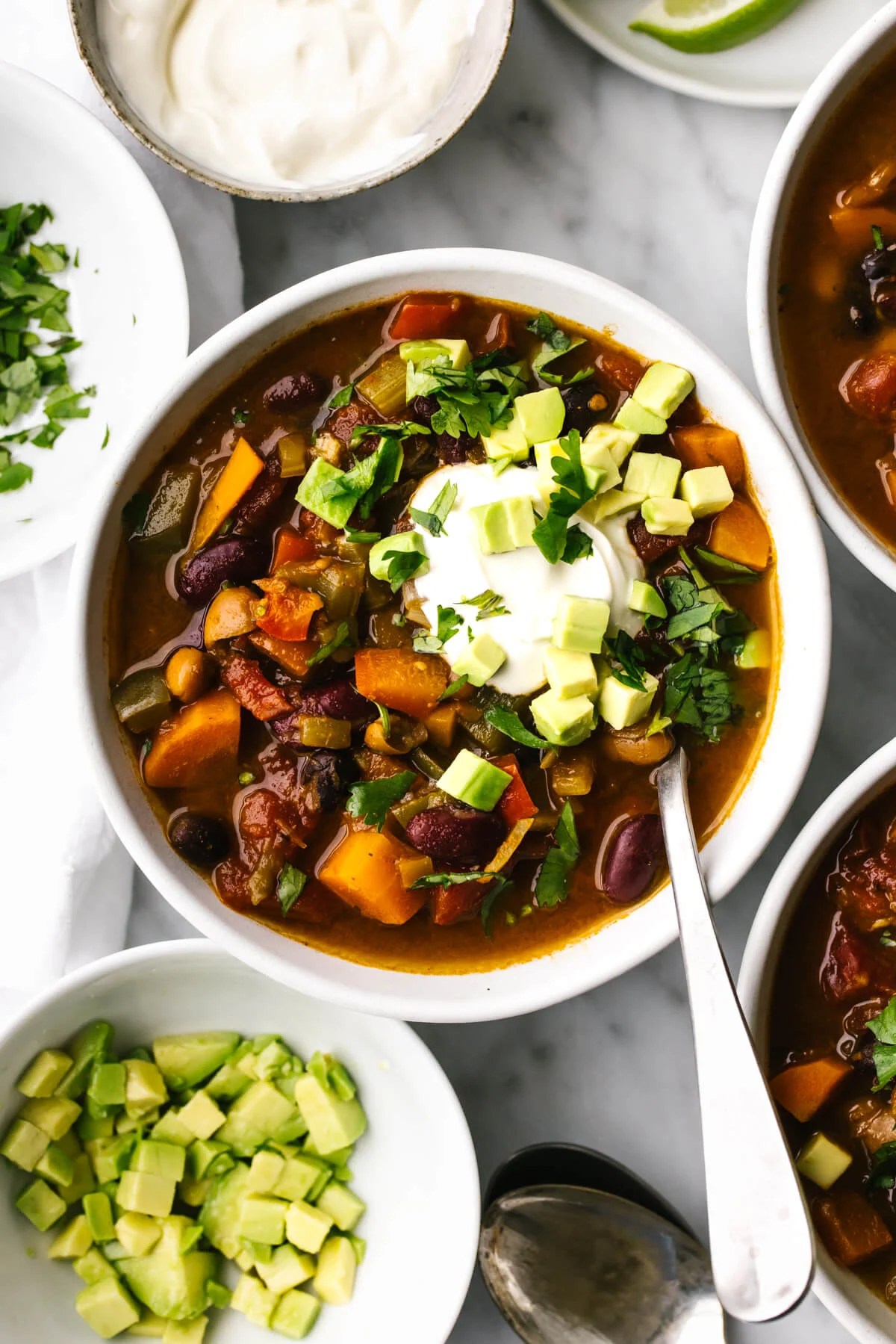 A bowl of vegetarian chili next to diced avocado.