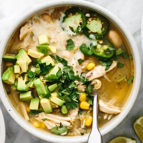 White chicken chili on a table with toppings.