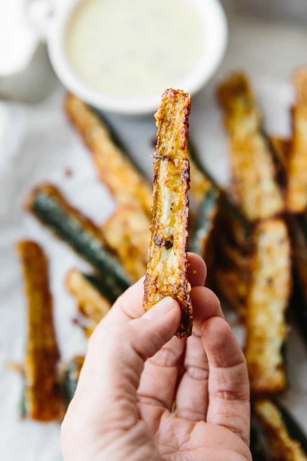 Hand holding a single zucchini fry.