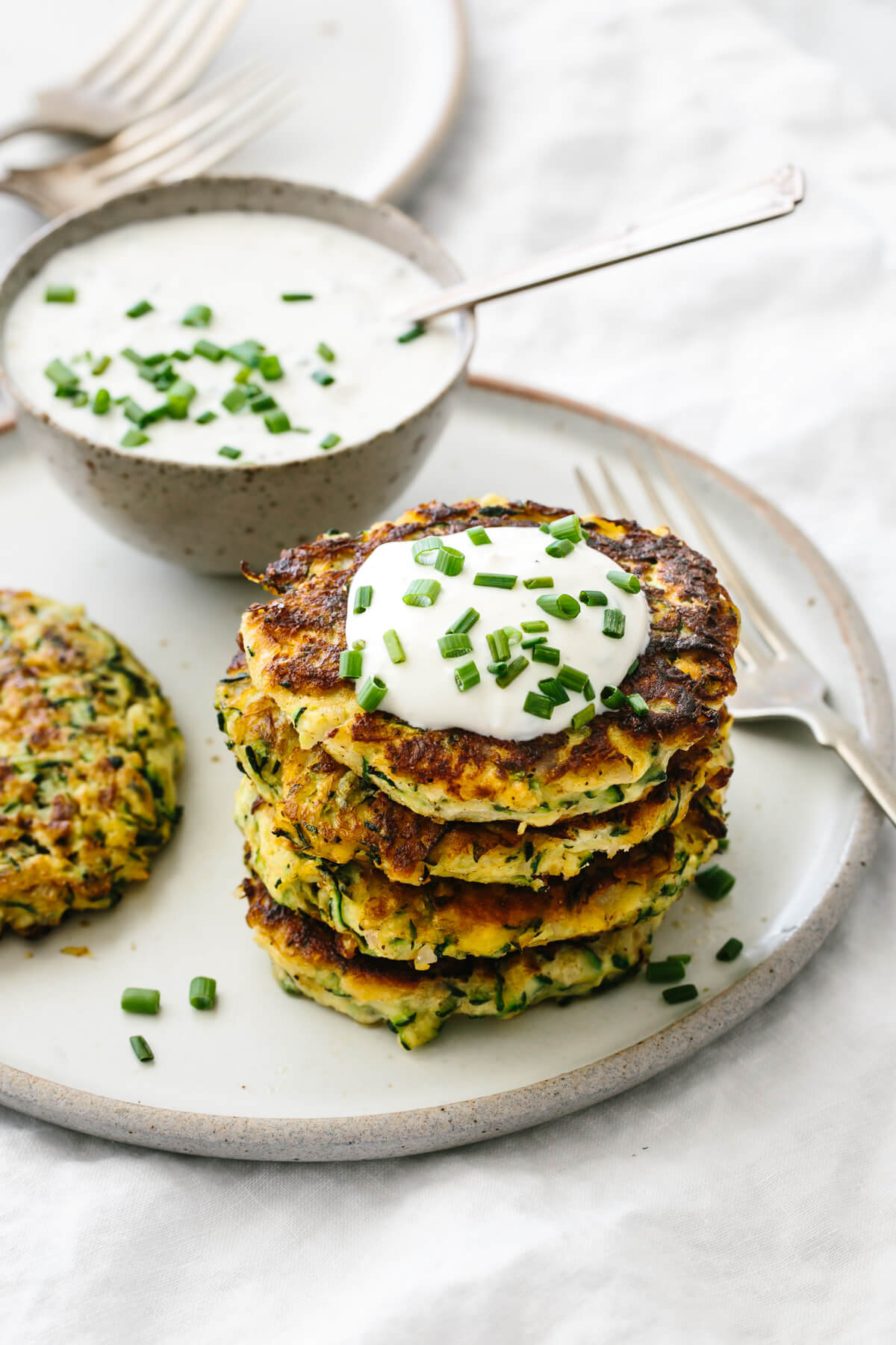 A stack of zucchini fritters with a dollop of sauce.